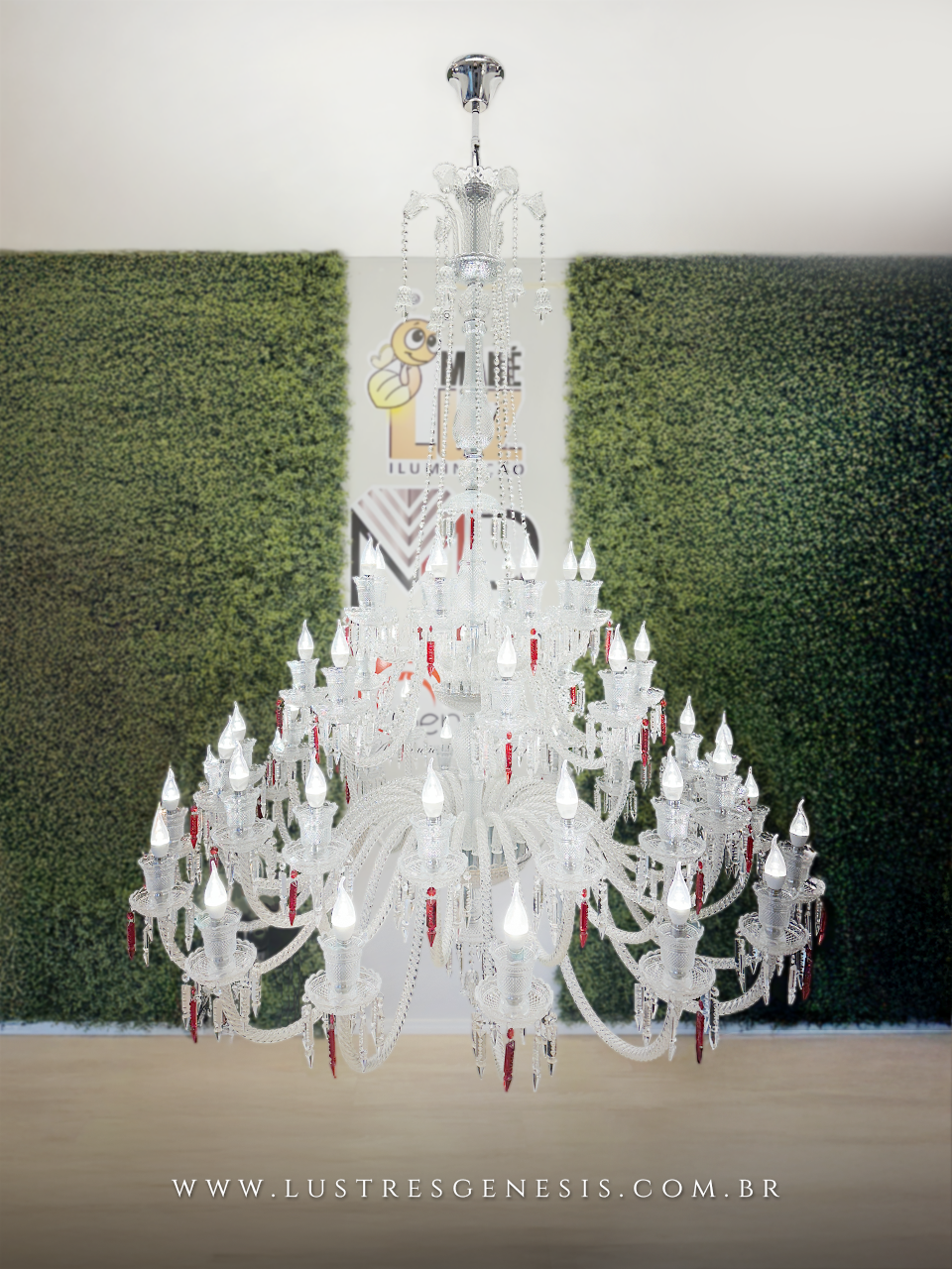 Lustre de teto sofisticado, com estrutura em cristal, iluminado por várias lâmpadas e decorado com pingentes em cristal vermelho.